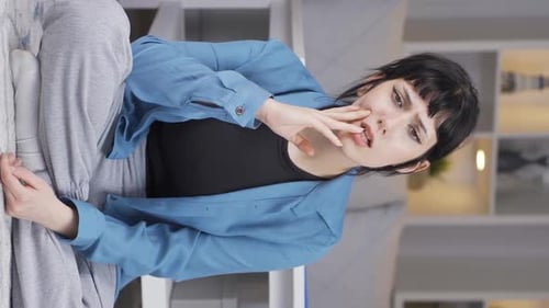 Vertical video of The pessimistic young woman is confused at home.