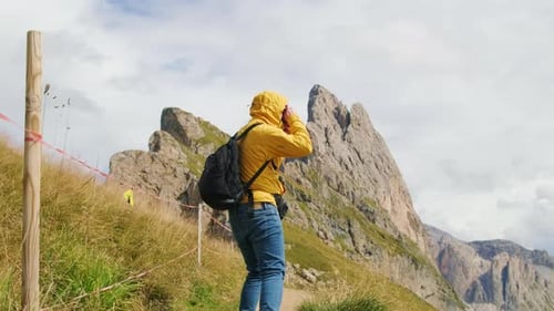 Un homme avec un sac à dos prend des photos de la montagne géante de Seceda