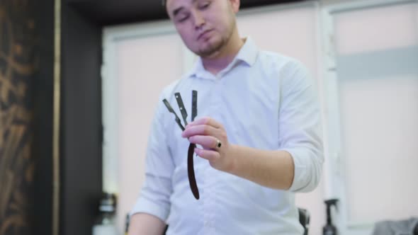 The barber holds a straight razor in its hands and pushes it apart ...