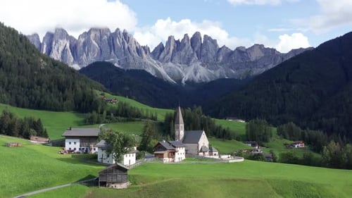 Small mountain village with church under Dolomites mountains in Italy, Val Di Funes aerial. St. Magd