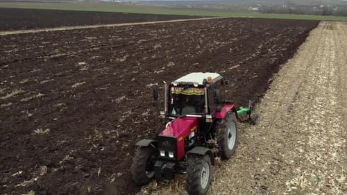 Red tractor plowing the field in Ukraine