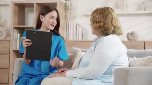 Caregiver sitting on sofa checkup and diagnostic with elderly woman patient about health.