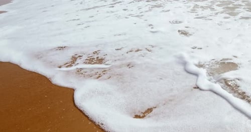 Soft White Ocean Waves Crashing Gently On A Sandy Beach