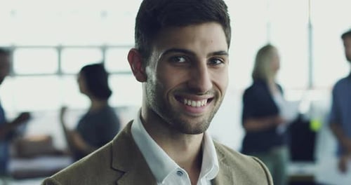 4K video footage of a young man standing in a modern office with coworkers in the background
