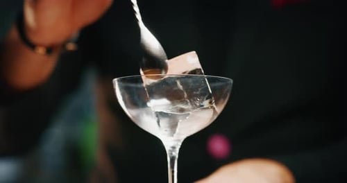 De perto, um barman profissional está preparando um coquetel alcoólico com cubos de gelo para o cliente