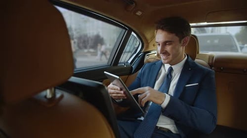 Smiling Man Using Tablet in Car Back Seat