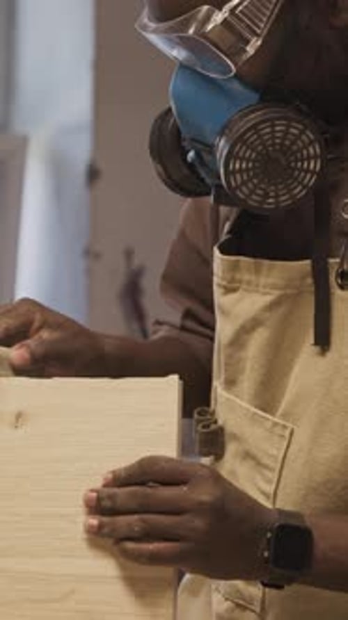 African American Woodworker Hand Sanding Wooden Board in Workshop
