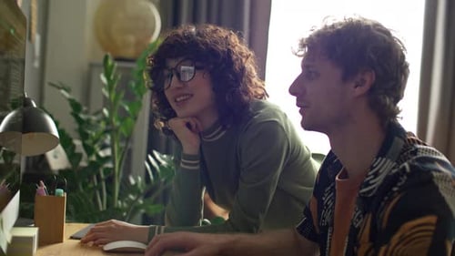 Junges Paar diskutiert zu Hause auf dem Computerbildschirm über Programmiercode