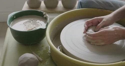 Un potier travaillant au moulin à poterie fabriquant une tasse.