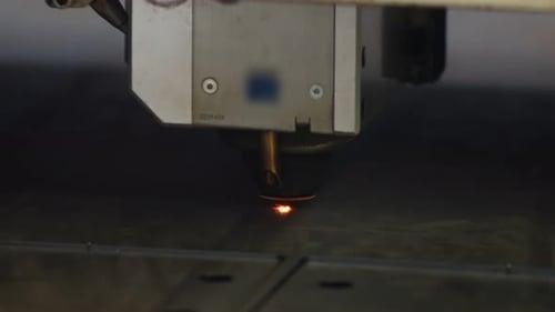 Nahaufnahme einer Laserschneid-CNC-Maschine, die im Werk Löcher in Bleche mit vielen Funken bohrt