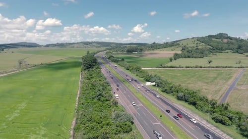 Highway road traffic with cars and trucks aerial forward view in green rural landscape