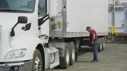 Truck driver prepares cargo trailer for delivery on the open highway