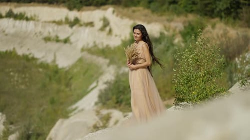 Sanfte junge Frau in einem langen festlichen Kleid mit einem Blumenstrauß