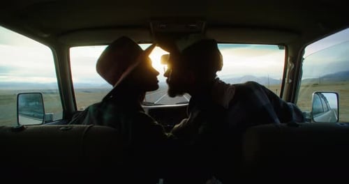 Young Couple Kissing in Car During Road Trip at Sunset