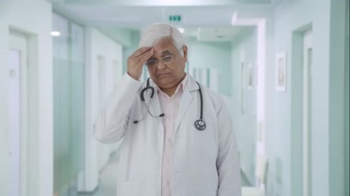 Pensive Doctor Standing in Hospital Corridor