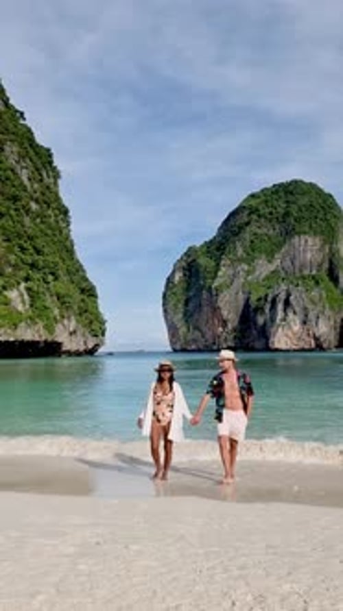 Couple Enjoying a Serene Beach Walk on Koh Phi Phi in Thailand with Stunning Cliffs and Clear Waters