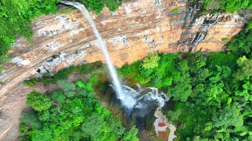 Aerial view: Majestic waterfall cascades from cliff.