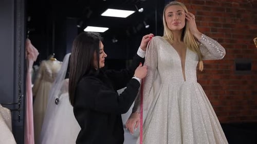 O vendedor/consultor do salão de casamento ajuda a noiva cliente a escolher um vestido