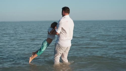 Father Plays with His Son While Swimming in the Sea