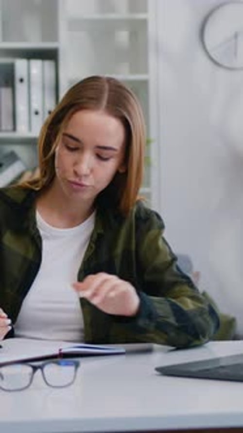 Woman Working on Laptop and Writing in Notebook