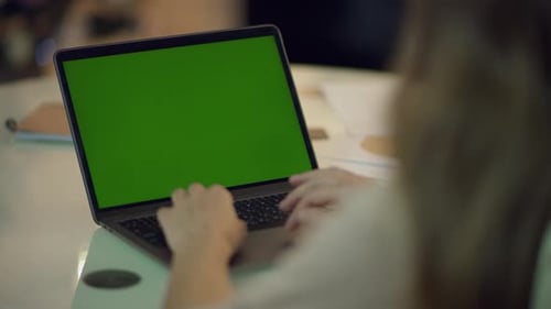 Woman typing on laptop keyboard with green screen at home during christmas