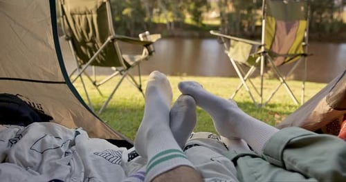 Camping, tent and feet of couple with love, romance and bond, rest and relax in a forest together