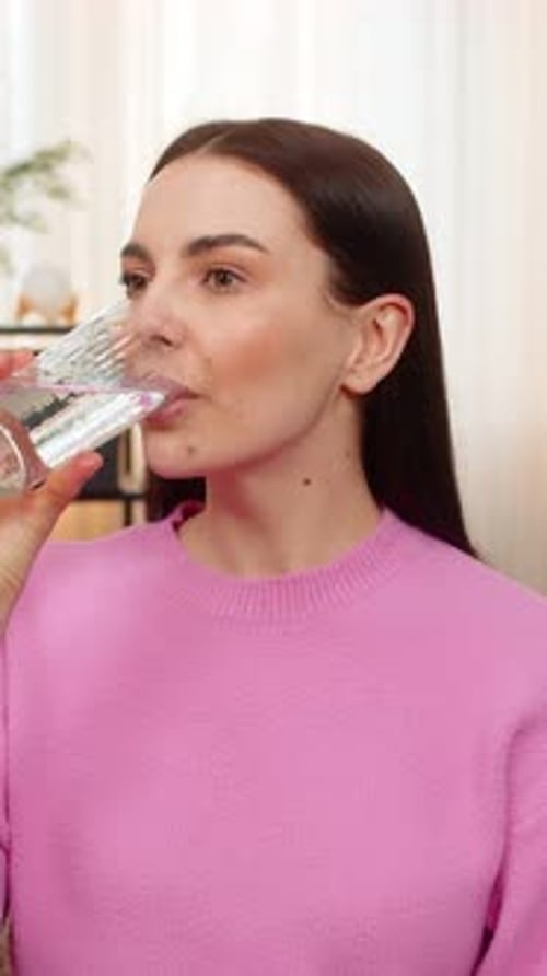 Woman Drinks Glass of Water Smiling Indoors