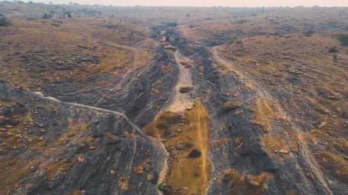 Cinematic Aerial drone flight over a dry riverbed ravine in a barren landscape drought conditions du