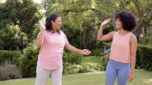 High-fiving, mother and adult daughter enjoying outdoor exercise in park, smiling and bonding