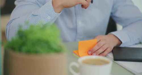 Adult Writing on a Sticky Note in Office