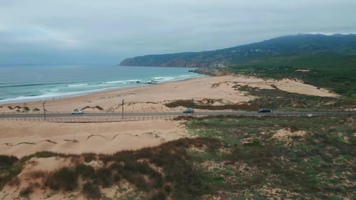Foamy Waves Washing Beach Lined with Sandy Dunes Drone View Road Stretching