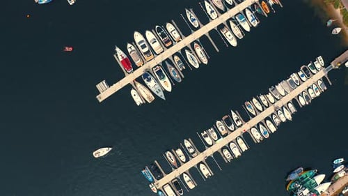 Drone view of the marina with moored yachts and motorboats and small yacht sailing in the middle