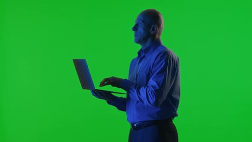 Rechenzentrumsspezialist verwendet Laptop unter Neonlicht auf Chroma-Key-Hintergrund