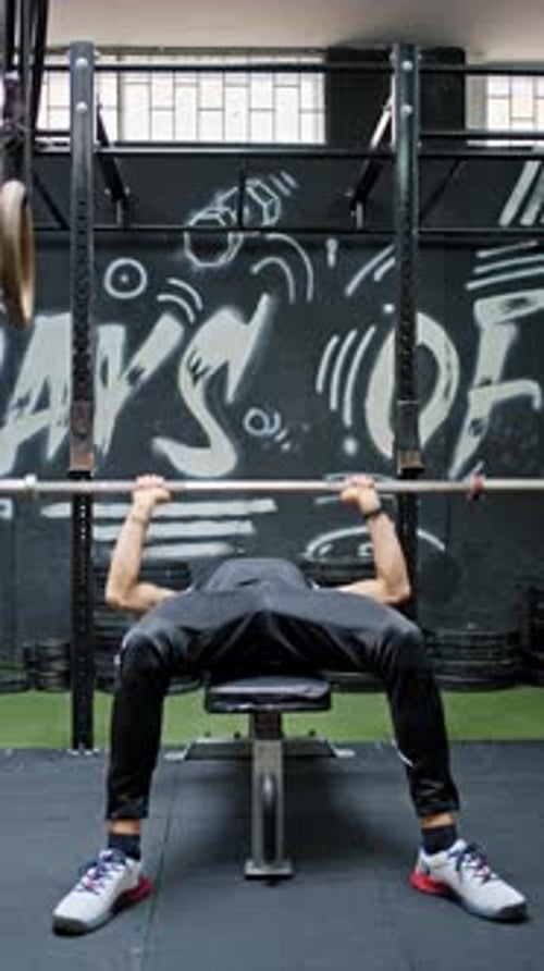 Man Weightlifting Barbell on Bench in Gym