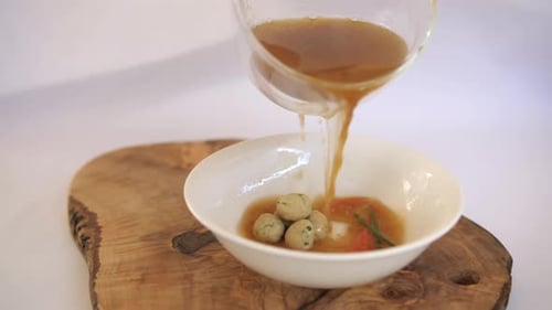 Broth Being Poured Into Soup Bowl With Meatballs