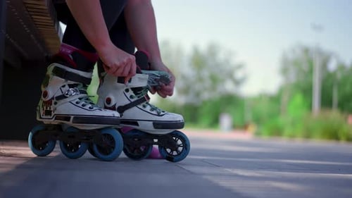 young hipster girl puts on roller skates in skate park before starting skating street extreme sport