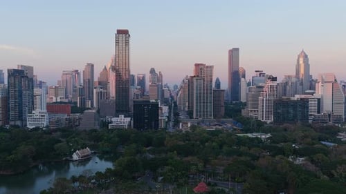 Unique Tripod Aerial View of Bangkok Skyline with Modern Skyscrapers and Lumphini Park During Sunset