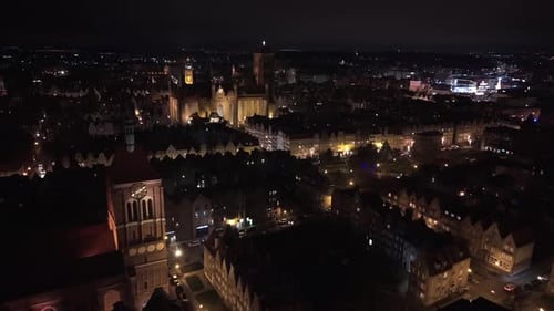 Nachtaufnahme der Danziger Altstadt mit Blick auf das beleuchtete Alte Rathaus und die hoch aufragende St.