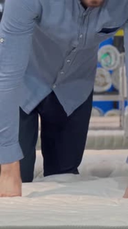 Handsome Man Testing Orthopedic Mattress While Lounging on a Stylish Bed in a Store