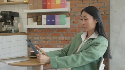 Focused Woman Working On Digital Tablet With Cup Of Coffee In Modern Cafe