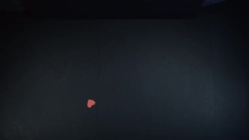 Heart shaped red papers falling on black table, Woman's hands in shot. Above shot with the Sony a7ii