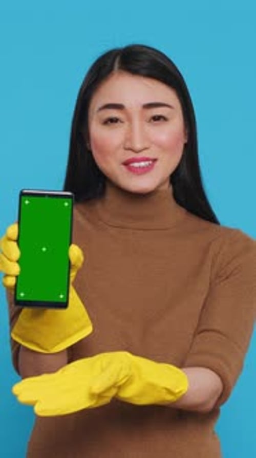 Vertical Video Asian Homemaker Holding Chroma Key Mock Up Mobile Phone with Greenscreen Display