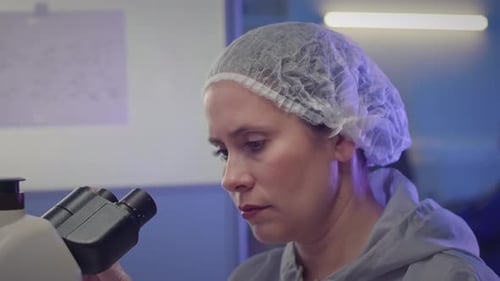 Woman Scientist Looking Through Microscope in Laboratory