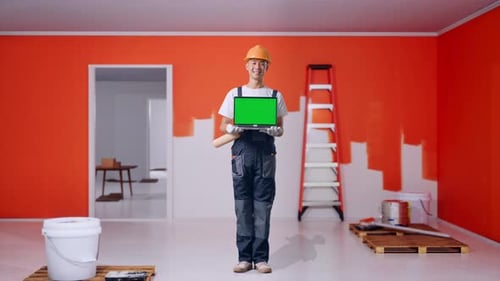 Full Body Of Asian Man Painter Smiling And Showing Green Screen Laptop With Painting Wall In Room