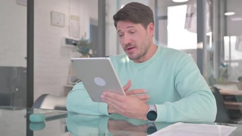 Man Talking on Tablet Video Call in Office
