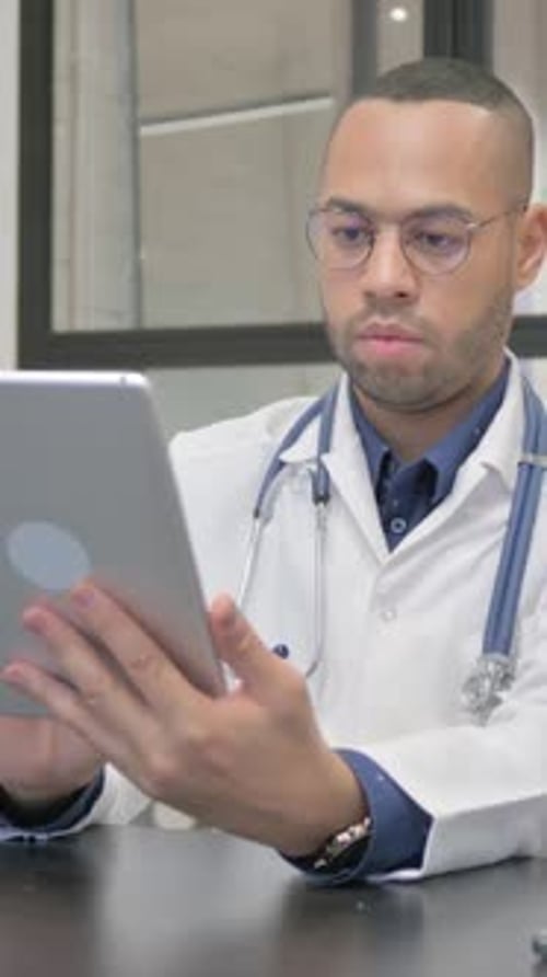 Concentrated Doctor Uses Tablet in Modern Office