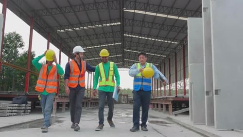 Grupo de ingenieros o contratistas del equipo que sostienen un casco, se relajan y hablan con Happy en el sitio de construcción.