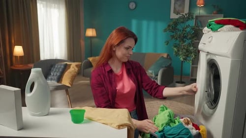 Woman Loading Clothes Into Washing Machine