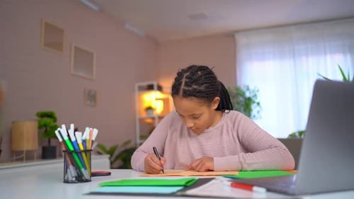 Girl Drawing at Desk with Markers and Laptop