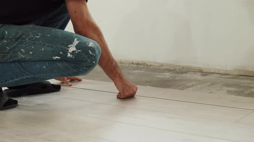 Man Installing Laminate Flooring Inside a House